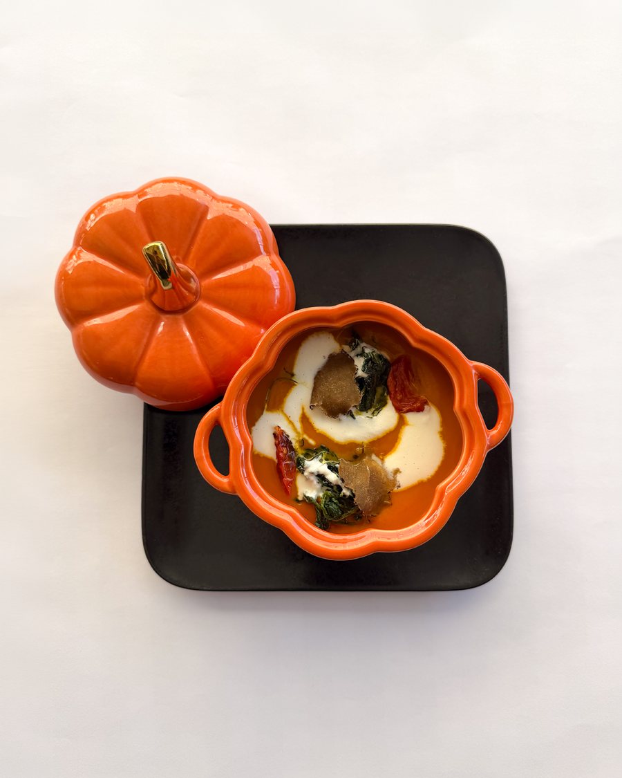 Vellutata di zucca e tartufo con stracciatella e cicoria, servita in una cocotte a forma di zucca